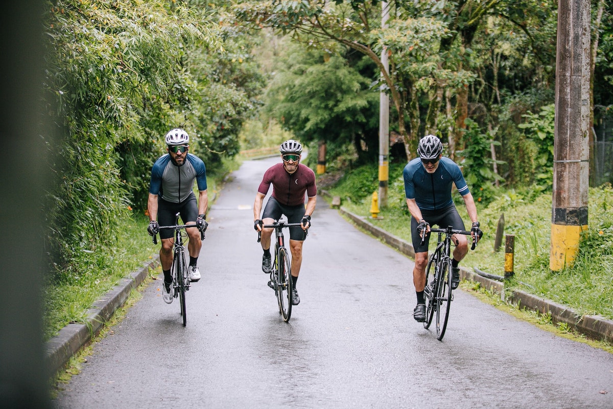 Three cyclists riding together on an empty road.