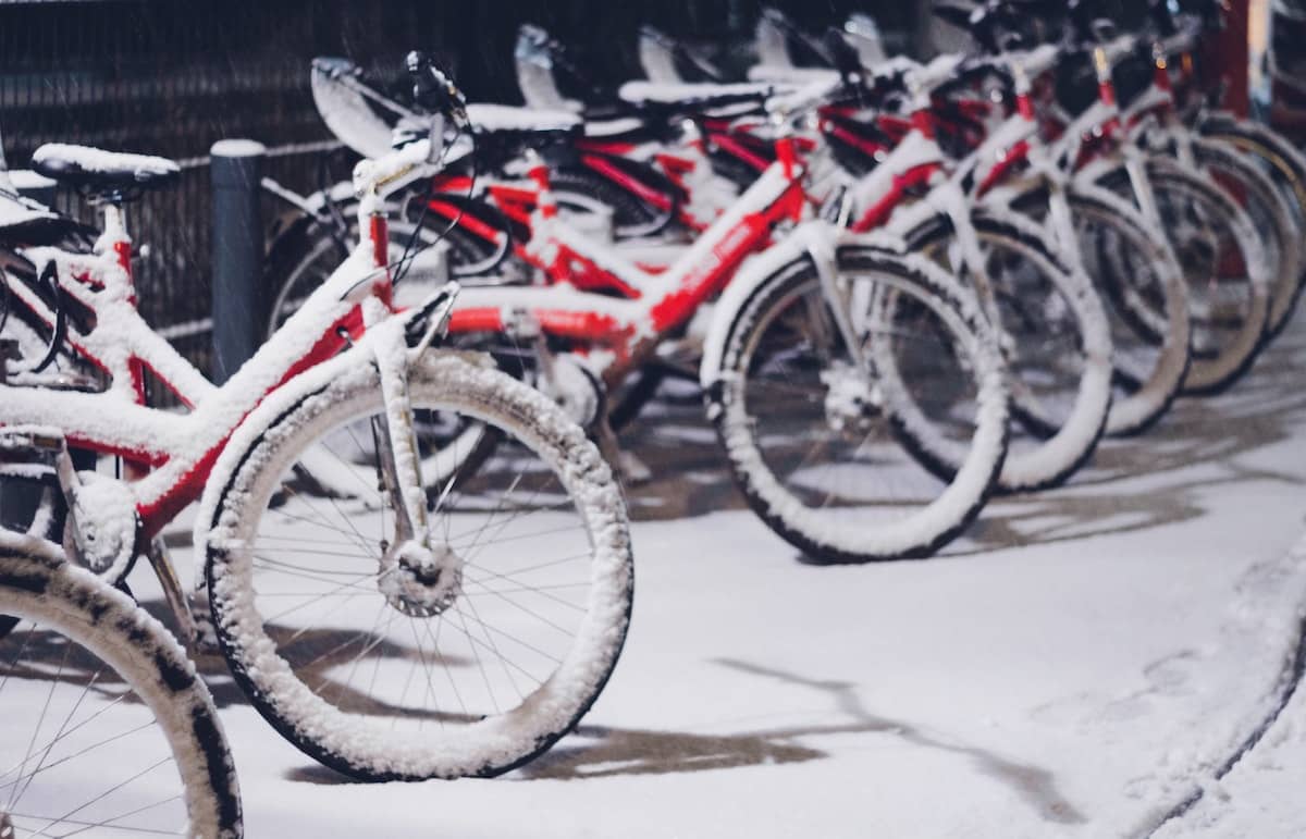 A row of red winter bikes, covered in snow. 