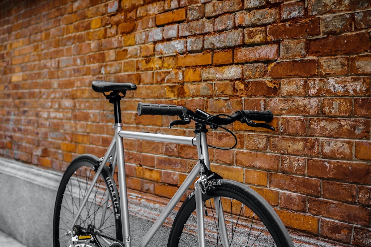 A silver bike against a brick background.