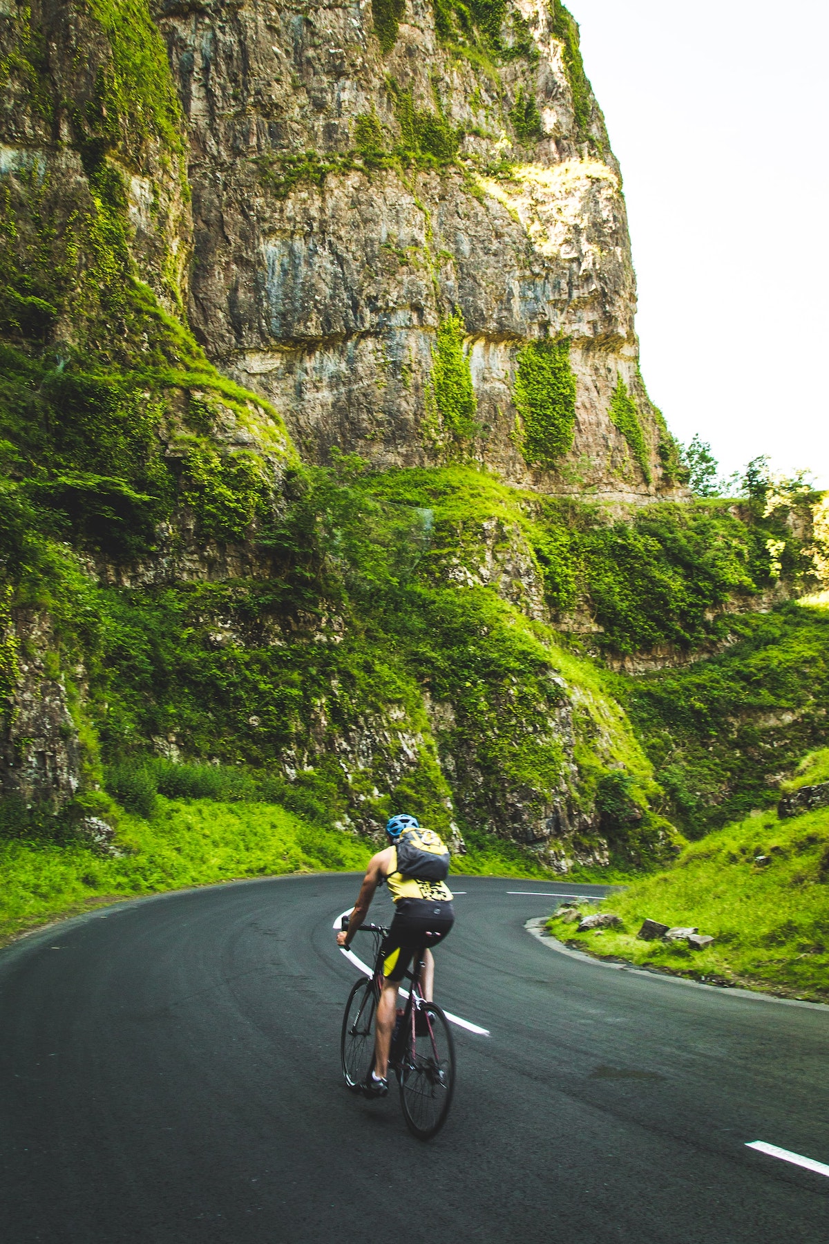 A cyclist wearing elastic waist shorts rides amidst green hills.