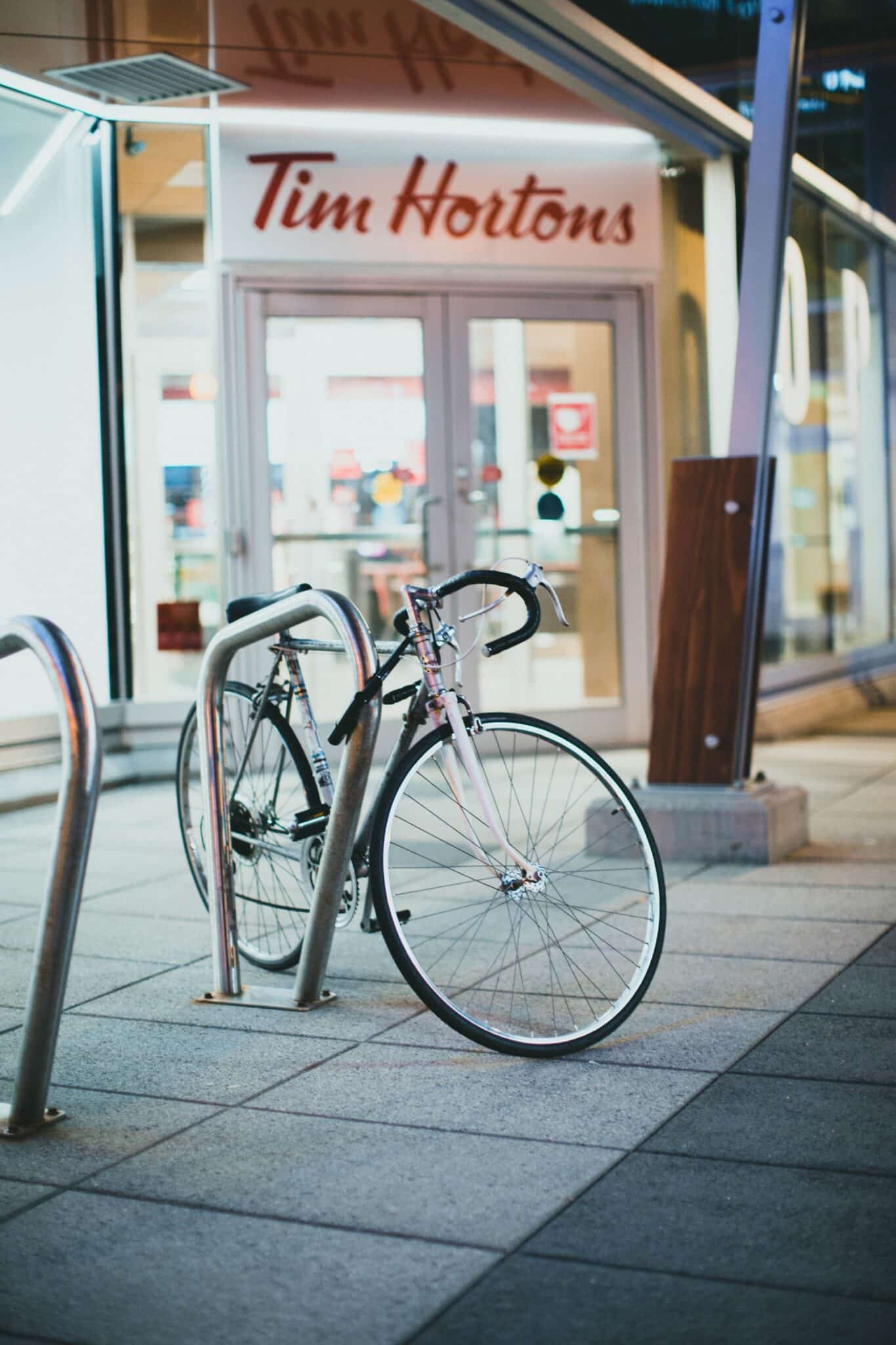 A bicycle locked to bike stand in front of a Tim Horton's.